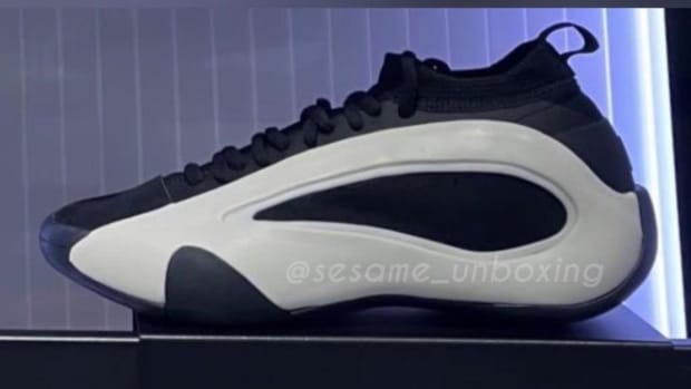 Side view of white and black adidas shoes.
